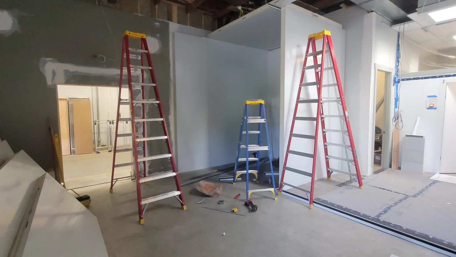 Wall panels going up during a walk-in cooler build, with ladders and tools on the floor
