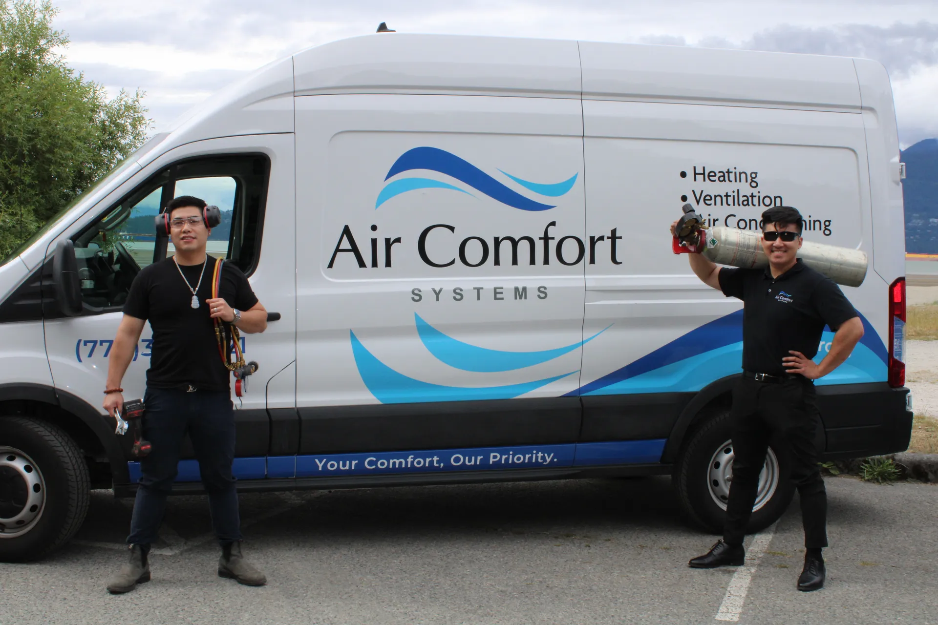 Ed and Larry of Air Comfort Systems holding their tools in front of a service van